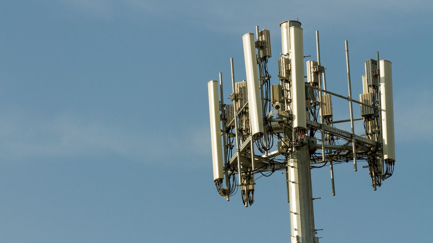 Close-up telecom antenna array against open sky.